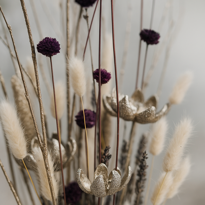 Close-up of the Winter Plum Dried Floral Arrangement showing deep plum blooms, golden glittered seed pods, and soft cream grasses with natural texture and depth